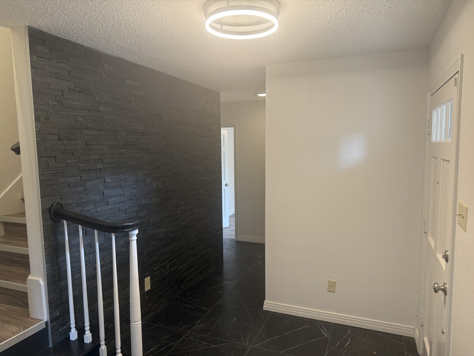 Entry foyer with stone accent wall and staircase